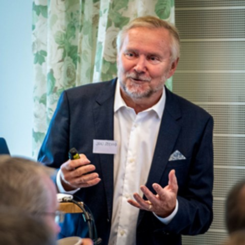 A man is giving a talk and smiles. Photo.