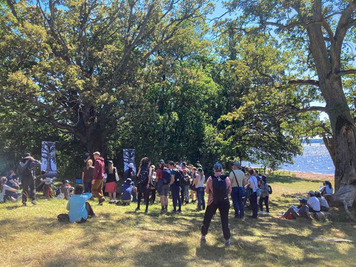 En grupp människor som står på ett fält vid träd. Foto.