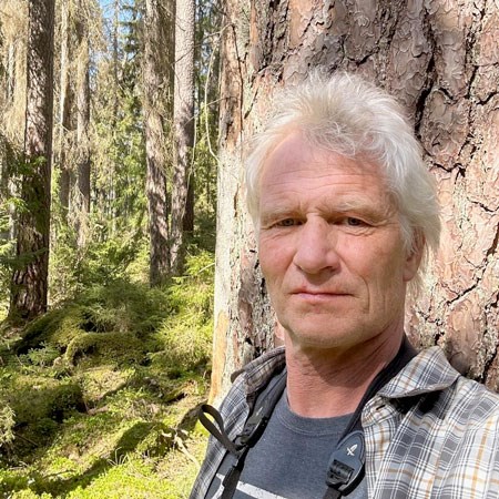 Porträttfoto av en man i skogen.