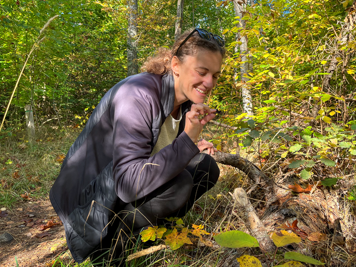 Francesca sitter bredvid ett fallet träd och luktar på en bit mossa.