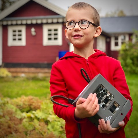 Kid holding a camera trap. Photo.