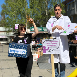 Forskare i labbrock håller presentation på torget. Foto.