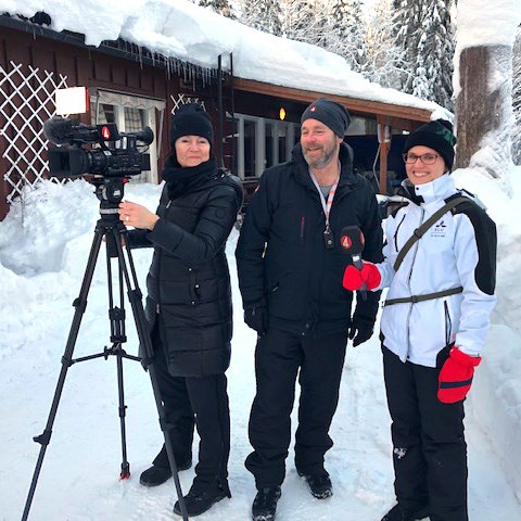 Tre personer utomhus vintertid vid en filmkamera. Foto.