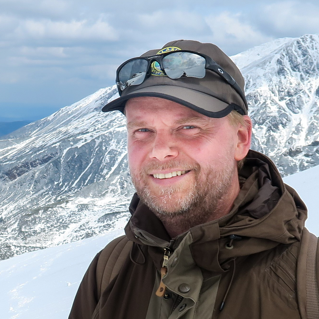 Man bland snöiga fjäll. Foto.