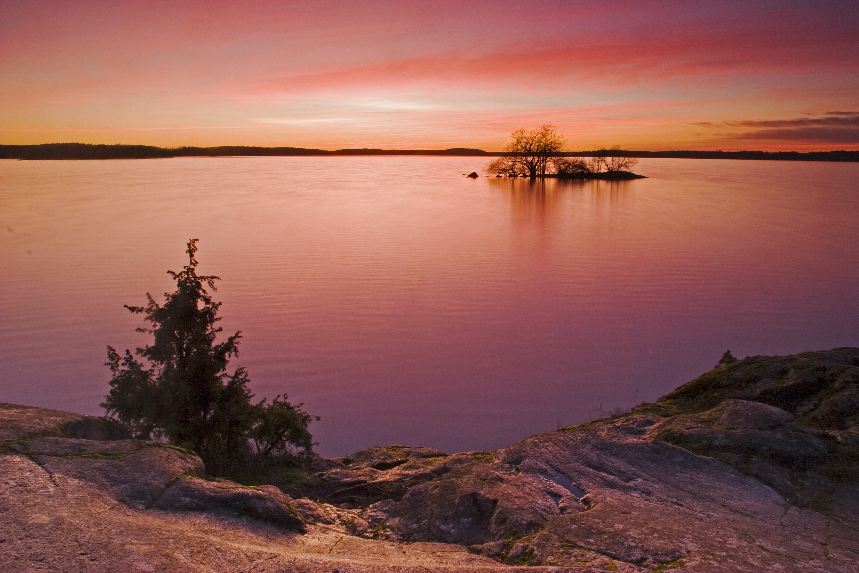 Solnedgång över sjö. Foto.