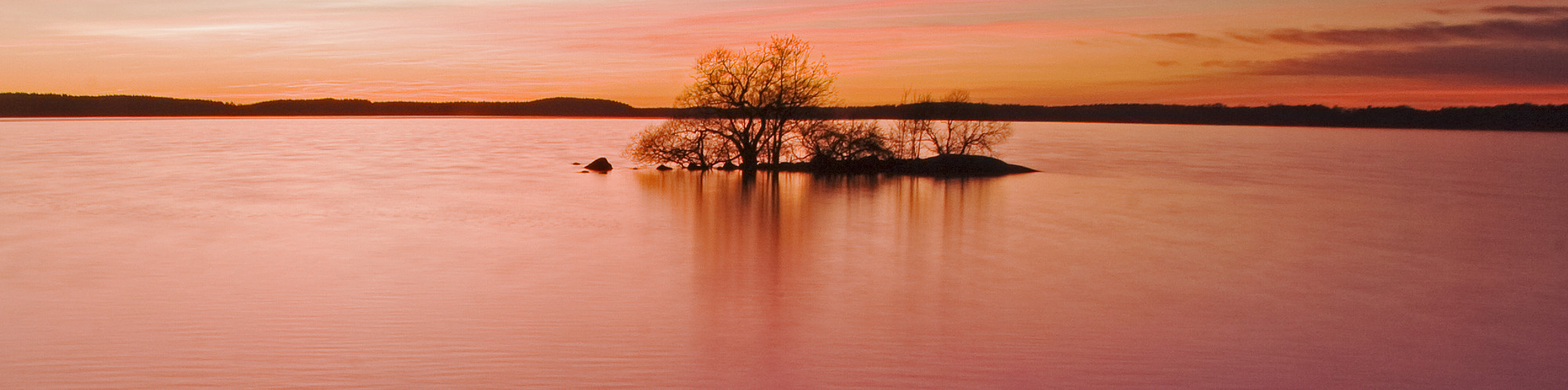 Solnedgång över en sjö. Himlen är röd. Foto.