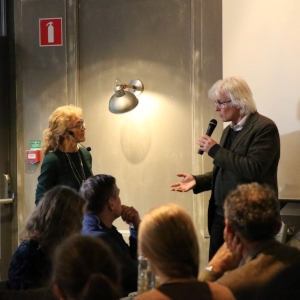 Man holding a microphone answering questions from the audience. Photo.