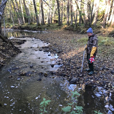 Man standing in watercourse. Photo.