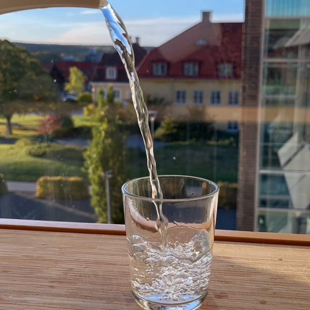 vatten hälls i dricksglas. Foto.