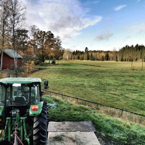 traktor med fält i bakgrunden. Foto.