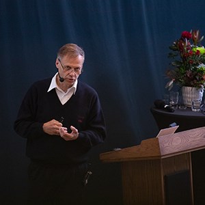En man står vid ett podium och pratar.