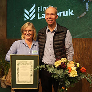 En kvinna håller i ett diplom och en man håller i en blombukett.