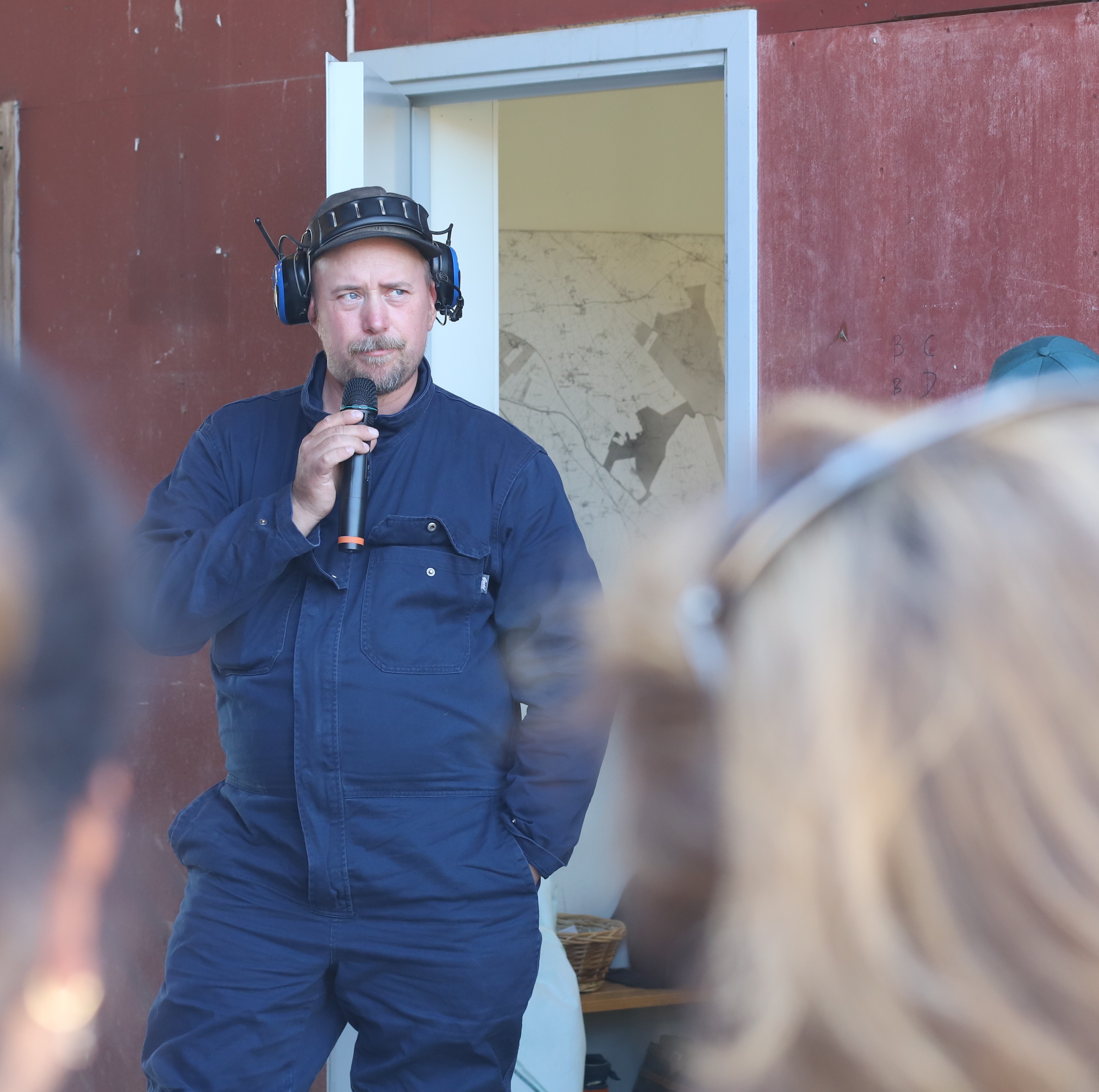 A man in work clothes speaks into a microphone.