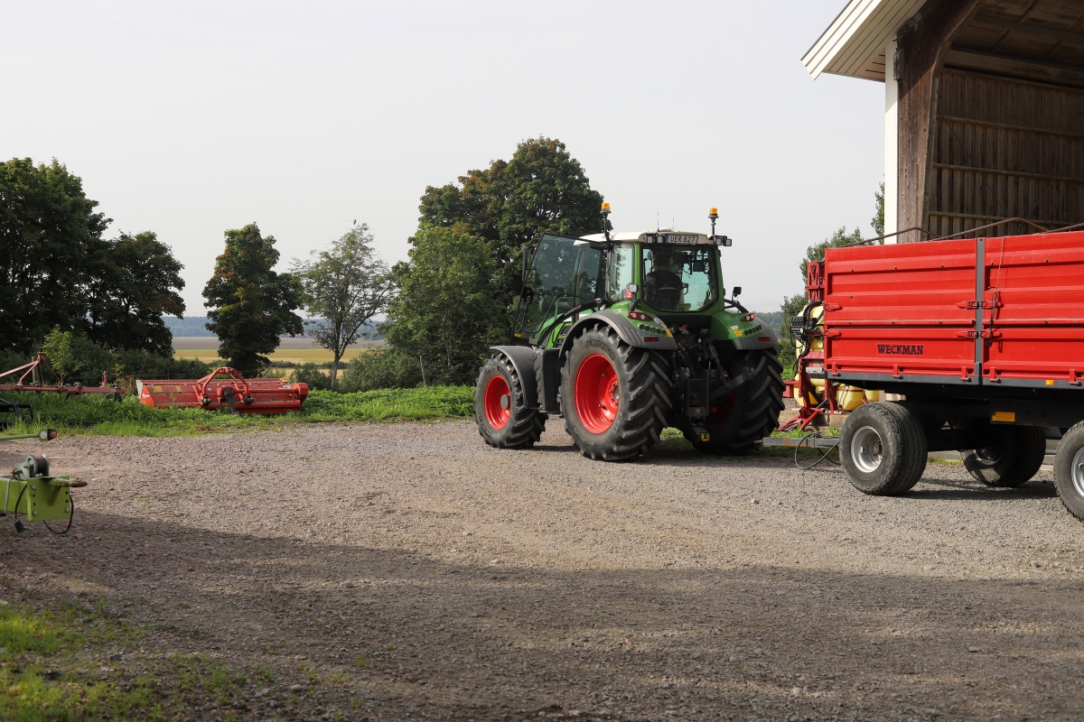 A tractor with a trailer in a yard.