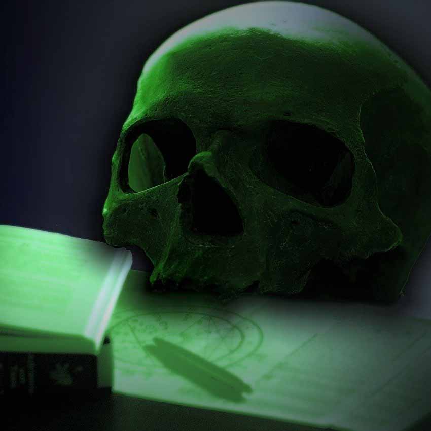 Human skull and some books in a spooky green light. 