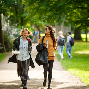 Two young women are walking in a park. Photo.