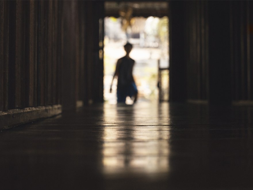 Man in backlight at the end of a dark corridor. Photo.