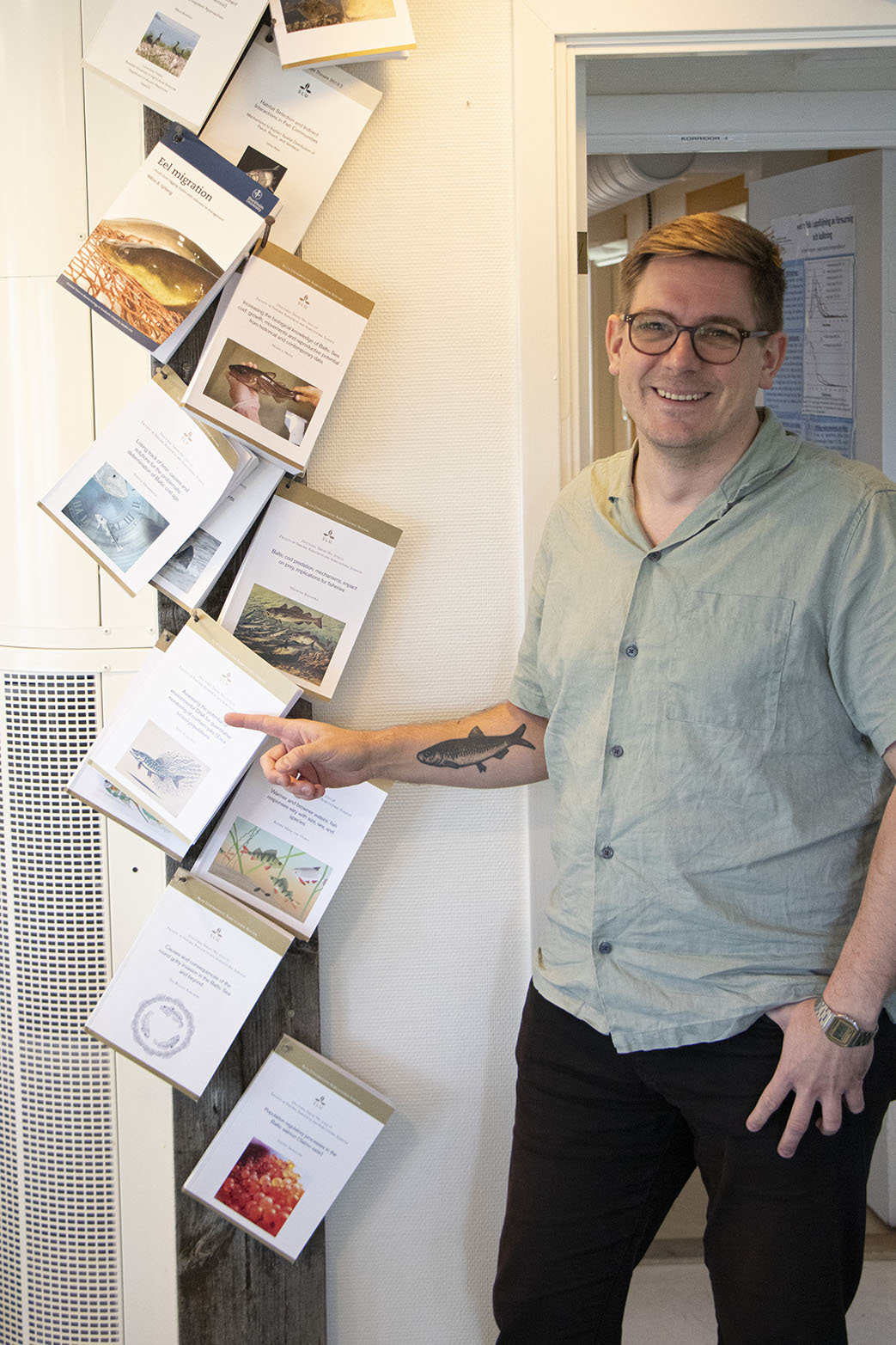 Erik står bredvid sin uppspikade avhandling