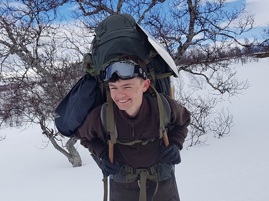 Ung man med ryggsäck i snölandskap. Foto.