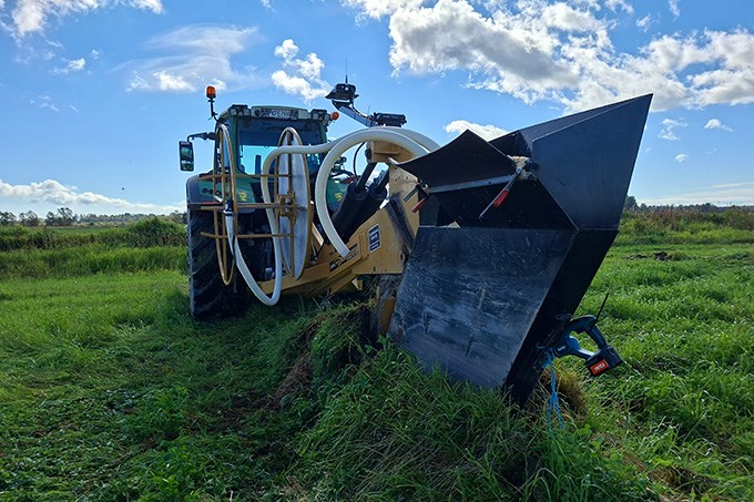 Traktor med stor plog lägger ner dräneringsrör. Foto.