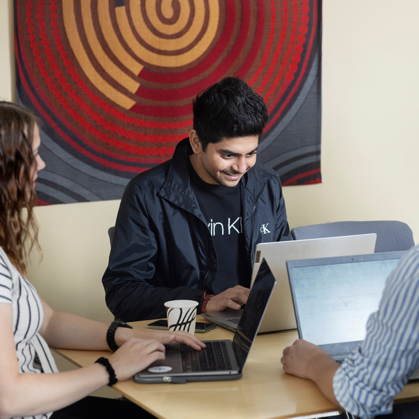 Students with laptops around a table.