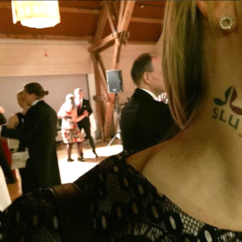 kvinna med en SLU.tatuering på halsen, foto