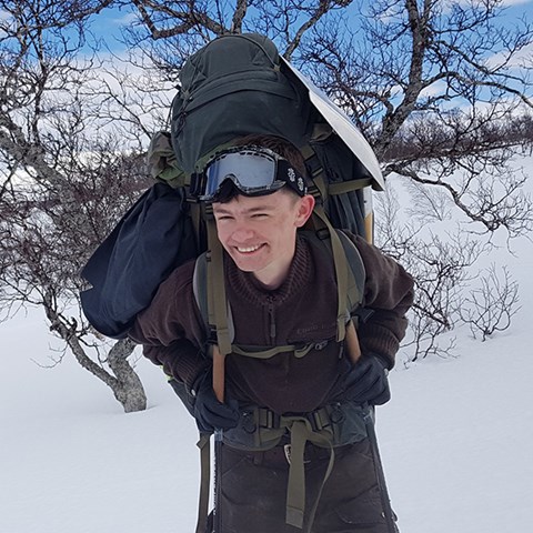 Ung man med ryggsäck i snölandskap. Foto.