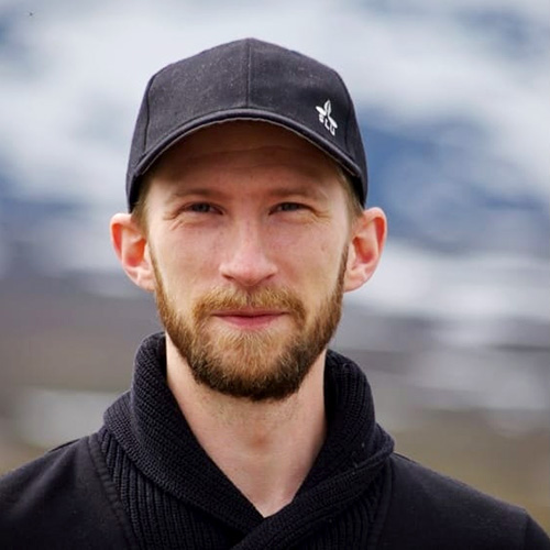 Ung man med i keps och blå stickad tröja. Foto. 