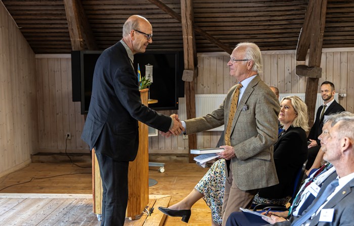 Professor Henrik Andrén överlämnar Grimsös jubileumsbok till Kungen.