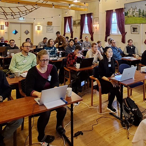 Group of people sitting at tables indoors. Photo.