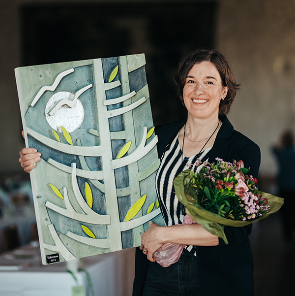 Kvinna som håller i en trätavla. Foto.