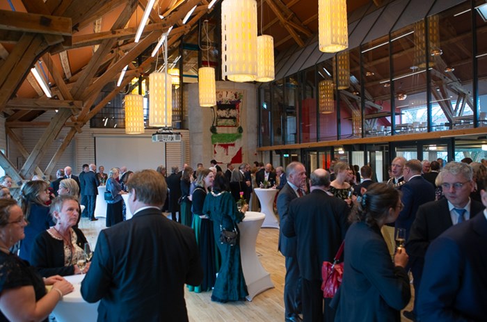 A room in an old barn, with high ceiling, people mingeling.