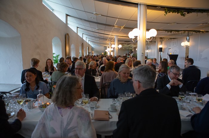 Dinner hall with long tables in many rows, white walls.
