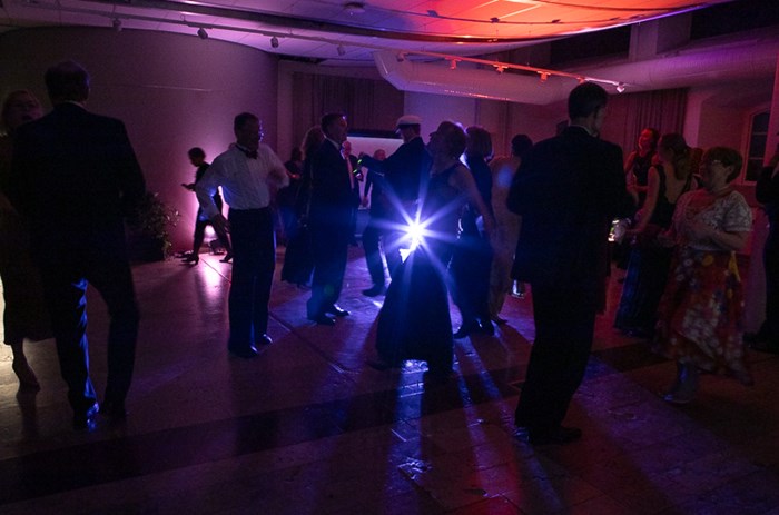 Dark blurry contours of people on a dance floor. Colourful light on walls and on the floor.