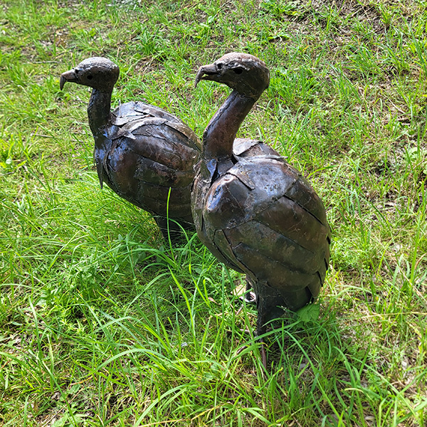 Två metallfåglar i grönt gräs. Foto.