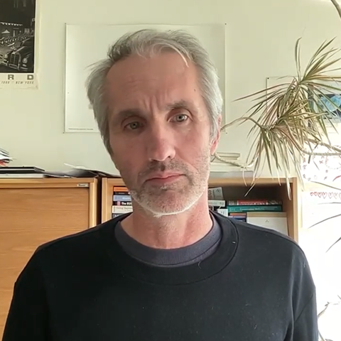 A man in a work room with book shelfs behid